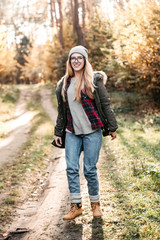 Fototapeta na wymiar Hiking and travel along in the forest. Concept of trekking, adventure and seasonal vacation. Young woman walking in woods.