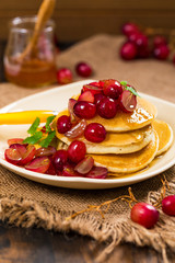 Stack of Pancakes with Sliced Red Grapes and Maple Syrup for breakfast. Selective focus.