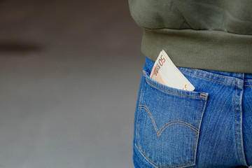 Back pocket of jeans close-up. A 50 Euro note sticks out of the pocket. The concept of business,...