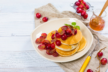 Stack of Pancakes with Sliced Red Grapes and Maple Syrup for breakfast. Selective focus.