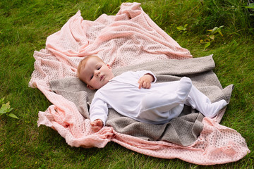  newborn baby in white clothes lies on  knitted blanket, view from above, healthy outdoor recreation