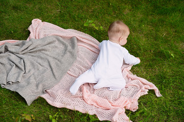 little child crawling on  knitted blanket, rest on  lawn, green grass is comfortable to play