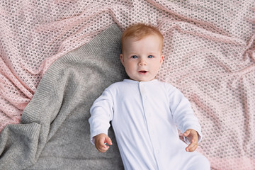  newborn baby in white clothes lies on  knitted blanket, view from above