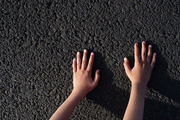 children's hands lie on  black road, conceptual image