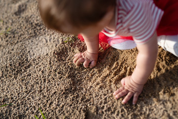 little girl touched  sand with her hand, view from above, sensory play