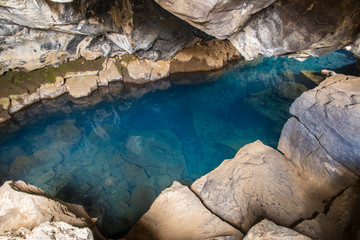 Natural Geothermal hot spring in the cave Grjotagja, Iceland blue water and colorful lava stones