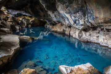 Natural Geothermal hot spring in the cave Grjotagja, Iceland blue water and colorful lava stones