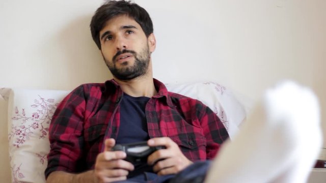 Handsome young millenial man playing video games in bed