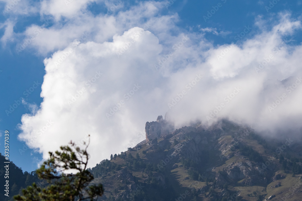 Wall mural Panorama montano di una cima di montagna contornata nelle nubi bianca che ne nascondo parte di essa