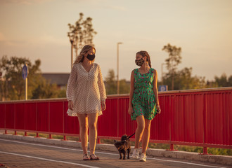 Naklejka premium Girlfriends walk the dog and wear face masks