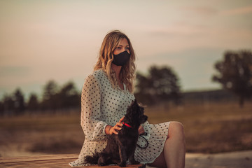 The girl enjoys walking with the dog and wears a mask on her face