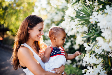 mother and daughter of mixed race looking at white flowers
