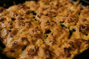 Meat cheese pizza. Baked meat in the oven lies on a black metal baking sheet. mouth-watering cheese sauce. 