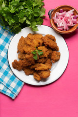 Fish chicharron with mayonnaise and onion on pink background
