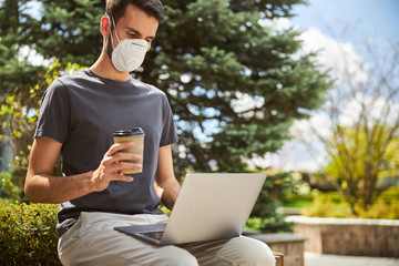 Man in a protective mask sitting outdoors