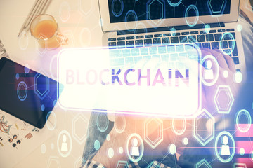 Double exposure of man's hands typing over computer keyboard and crypto currency theme hologram drawing. Top view. Blockchain concept.