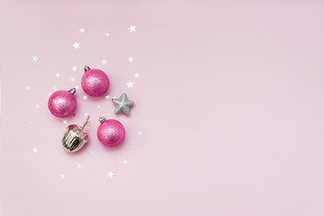 Pink and silver Christmas decorations on pink background with star confetti. New Year's decor for home. Selective focus.