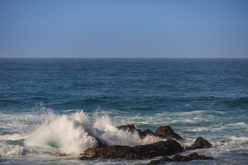 Waves breaking on large rocks in ocean
