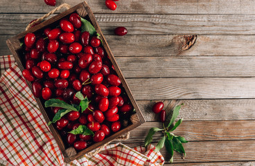 Dogwood berry in a wooden box. Ripe red cornel on rustic wooden background.
