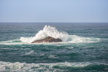 Fototapeta premium Waves breaking on large rock in ocean