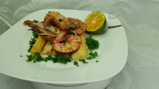 Traditional prawn with garlic and yuca as top view served in a white dish. Caribbean food concept. Close up view.