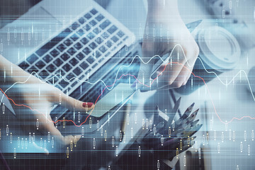 Double exposure of businesswoman hands typing on computer and financial graph hologram drawing. Stock market analysis concept.