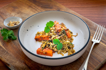 Vegan dish of roasted carrots and freekeh salad with coriander or cilantro