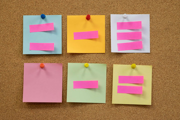Colorful reminder sticky notes push pins on cork board. empty free space.