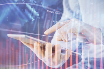 Double exposure of man's hands holding and using a digital device and forex graph drawing. Financial market concept.