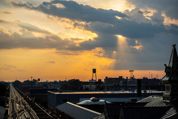 golden hour sunset of a beautiful Chicago urban area by the train station.   The sun raise peaks through the clouds in a ethereal warm orange glow.