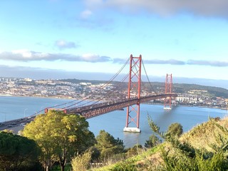 A statue of Cristo Rey and a view of the bridge named April 25 in Lisbon, Portugal.