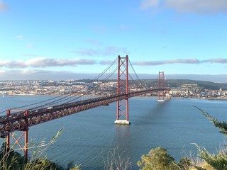 A statue of Cristo Rey and a view of the bridge named April 25 in Lisbon, Portugal.