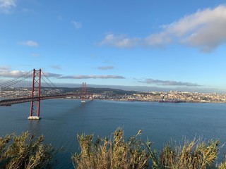 A statue of Cristo Rey and a view of the bridge named April 25 in Lisbon, Portugal.
