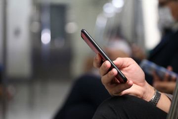 Hand of people holding cellphone while taking metro subway train to work with copy space