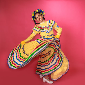 Bailarina vestida en traje tradicional folclórico mexicano amarillo en fondo rosa retrato