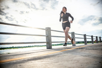 runner - woman running outdoors training for Exercise run.At the bridge at sunset. © Chanchai