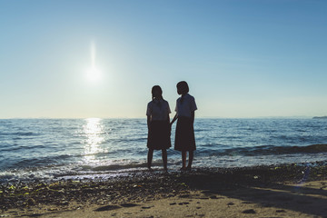 夕暮れの海にいる女子高生