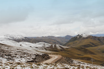 View of mountains with the snow on peak and dirt road in Tibet, China