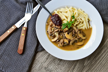 Brown button Mushroom slices Sour cream with soft egg noodle and wild cranberry jam.(German name is Champignon Rahm Geschnetzeltes mit Spätzle und Preiselbeermarmelade)