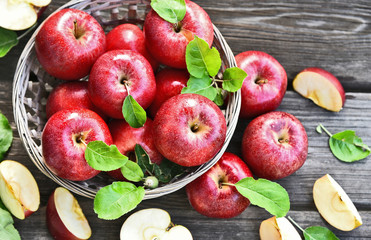 A lot of fresh Royal Red Gala apples with green leaf  in basket on wooden background.