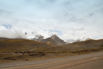 View of mountains with the snow on peak and dirt road in Tibet, China