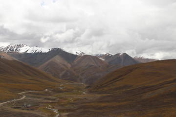 Fototapeta na wymiar View of mountains and dirt road with the dramatic sky in Tibet, China