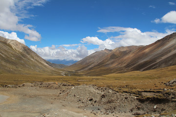 View of mountains and dirt road with the dramatic sky in Tibet, China