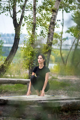 vertical photo of a Caucasian woman who does yoga and stretches in nature against the background of a forest