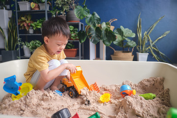 Cute Asian young boy playing with sand alone at home, Kid playing with sand toys & toy construction...
