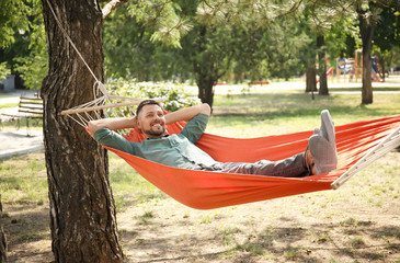 Handsome man relaxing in hammock outdoors