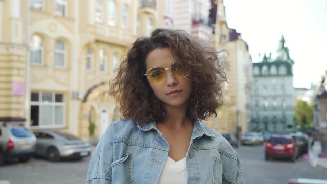 Closeup portrait of a happy beautiful latin hispanic girl student wearing stylish eyeglasses, looking at camera. Young indian or middle eastern woman standing smiling outdoors.  Portrait, copy space