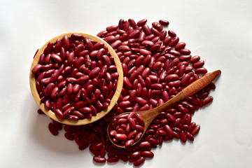 Closeup of Dried Red Kidney Bean are piled up, some in a wooden bowl and wooden spoon isolated on the white background, Full depth of field.