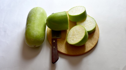 Fresh Green Winter Melon has been cut with a knife and a wood chopping block isolated on white background.