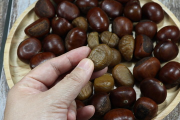 Traditional baked or roasted chestnut and peeled chestnut on the wooden plate. Famous local ingredients in Chinese cuisine. 